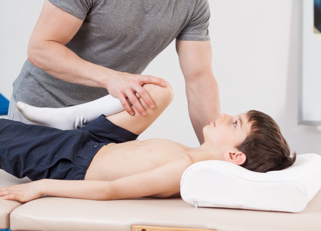 Male young physiotherapist working with little boy