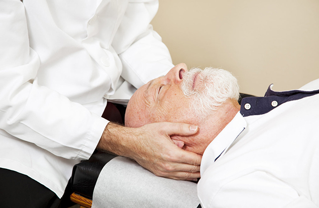 Closeup of a chiropractor adjusting a senior patient's cervical spine (neck).