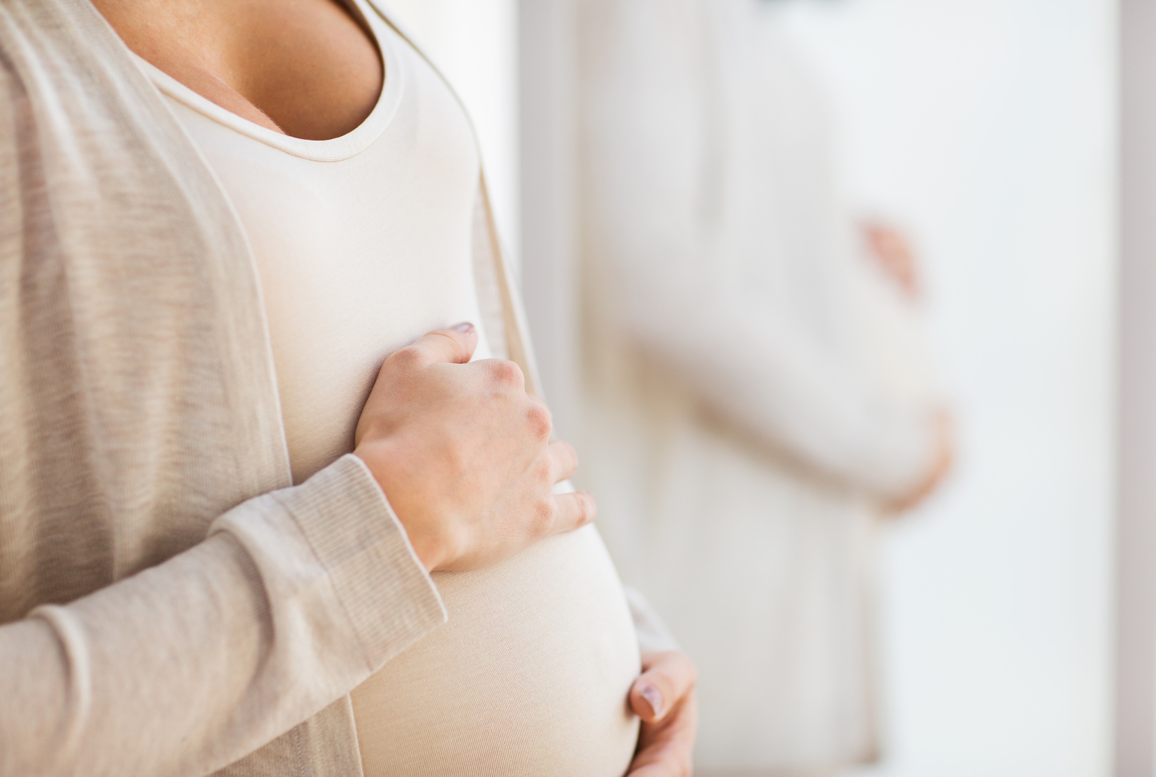 pregnancy, motherhood, people and expectation concept - close up of pregnant woman belly at mirror