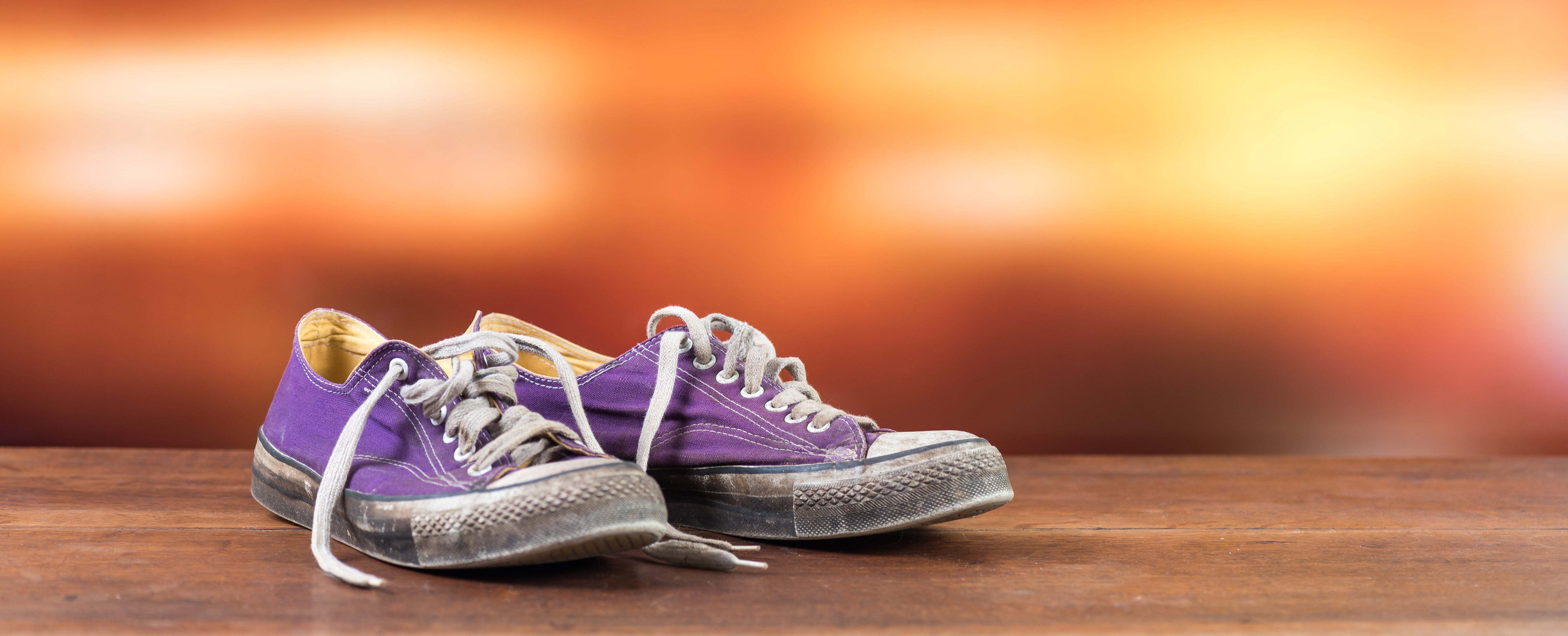 Old used purple sneakers on blurred background