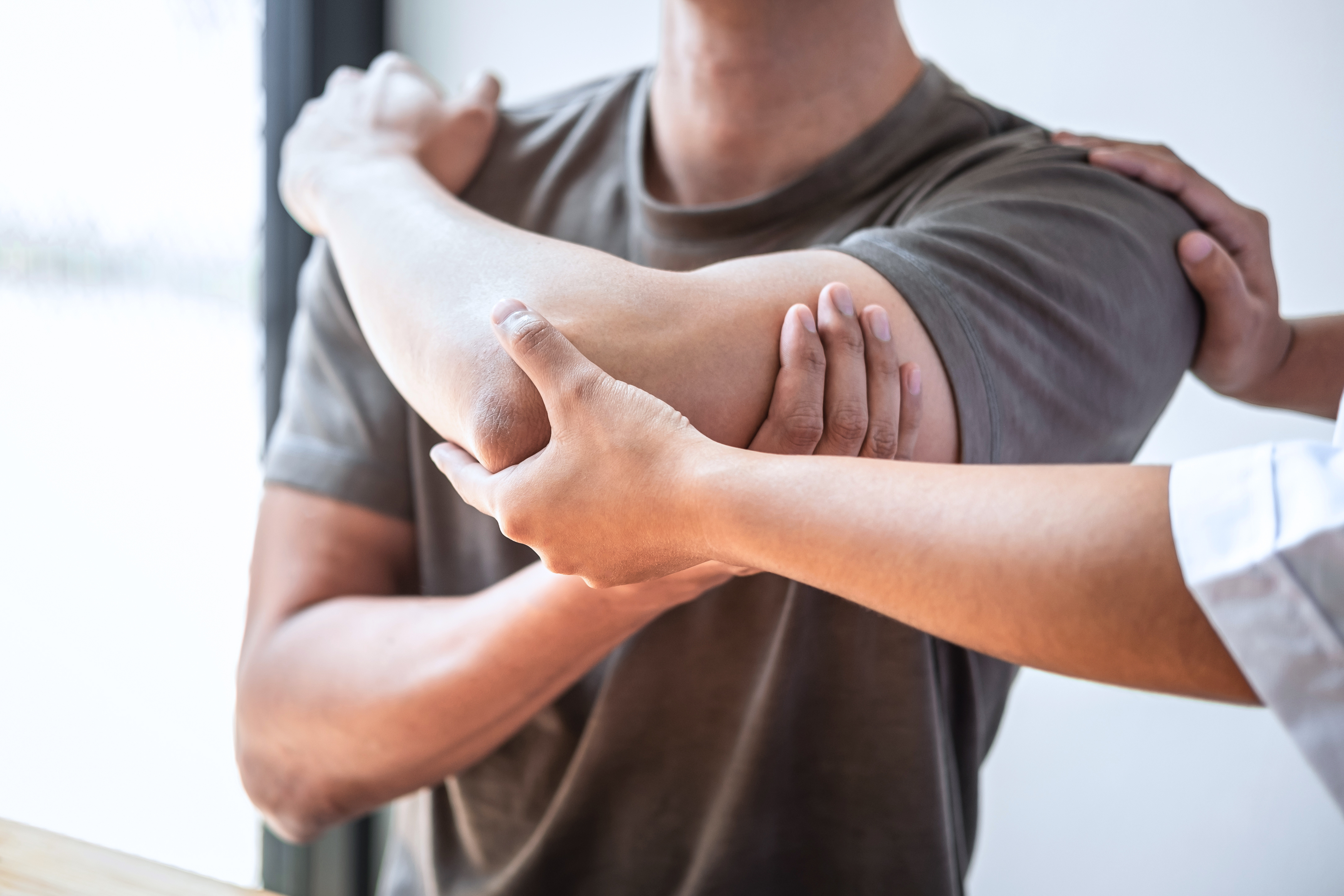 Female Physiotherapist working examining treating injured arm of athlete male patient, stretching and exercise, Doing the Rehabilitation therapy pain in clinic.